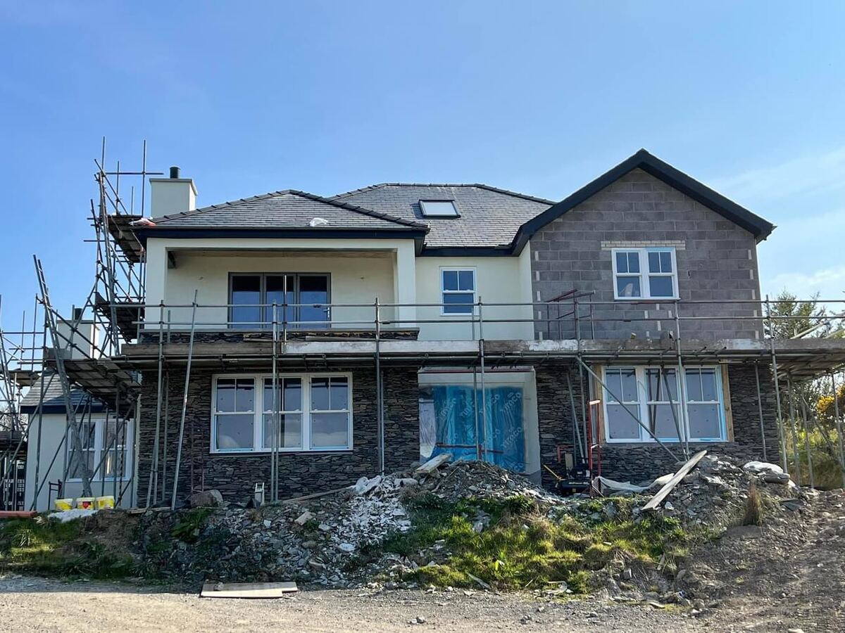 Stone-fronted house mid-render behind scaffolding